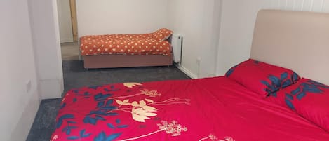 A bedroom with a large bed, a smaller bed, and a radiator.