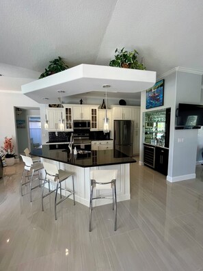 A modern kitchen with a central island, stainless steel appliances, and white cabinetry. - Gorgeous Private Retreat-Port St Lucie Pool (Port St. Lucie)