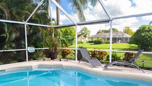 Ein Pool mit Liegestühlen und einer Topfpflanze, umgeben von einer Glasveranda.