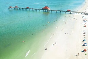 An aerial view of a beach with a pier extending into the water, featuring several red-roofed structures. - Heated Pool~Pickleball~Hot Tub~Game Room~Basketball~Fire Pit~Bunk Room~4 Kings (Tampa)