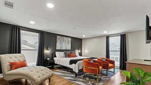 A modern bedroom with a large bed, a tufted armchair, a desk, and a potted plant. - Heated Pool~Pickleball~Hot Tub~Game Room~Basketball~Fire Pit~Bunk Room~4 Kings (Tampa)