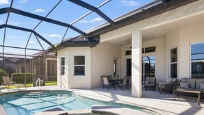 Un área de piscina con cerramiento de vidrio, mobiliario exterior y una terraza.