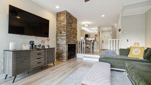 A modern living room with a flat-screen TV, a stone fireplace, a dining area, and a staircase leading to another level. - Quiet MTN Home w/ Fireplace, Minutes to Banner Elk (Banner Elk)