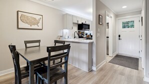 A modern kitchen with white cabinets, a central island, and a dining area with dark wooden chairs. - Quiet MTN Home w/ Fireplace, Minutes to Banner Elk (Banner Elk)
