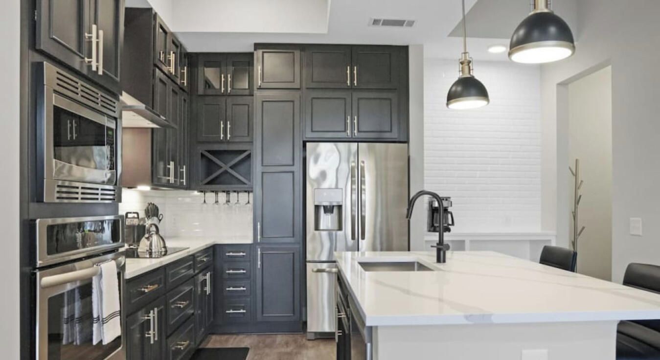 A modern kitchen with dark cabinetry, stainless appliances, and a central island.
