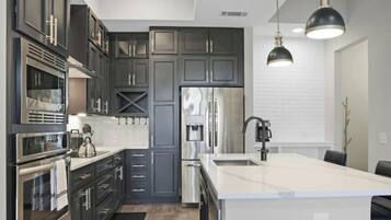 A modern kitchen with dark cabinetry, stainless appliances, and a central island.