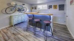 A compact kitchen with a bar area, wooden flooring, and a bicycle mounted on the wall.