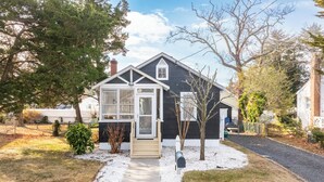 A two-story house with a front porch, a mailbox, and a small garden area. - Cozy Pet-Friendly Beach Cottage 2 Blocks from the Bay (Lower Township)