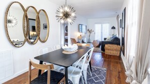 A dining area with a black table, white chairs, and three large gold-framed mirrors. - Cozy Pet-Friendly Beach Cottage 2 Blocks from the Bay (Lower Township)