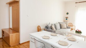 Eine moderne Küche mit Essbereich, Holzschränken und einem grauen Sofa.
