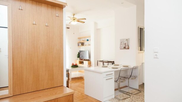 Eine moderne Küche mit weißen Schränken, einer zentralen Kochinsel und einem Deckenventilator.