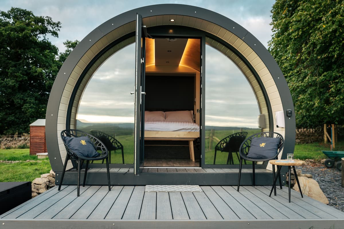 A circular room with a bed and two chairs, a small table, and a view of the landscape.