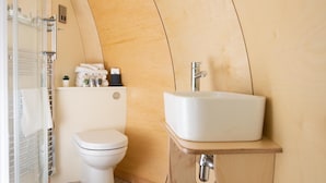 A compact bathroom with a toilet, a sink, and a shower enclosure. - Cardross Estate Glamping (Stirling)