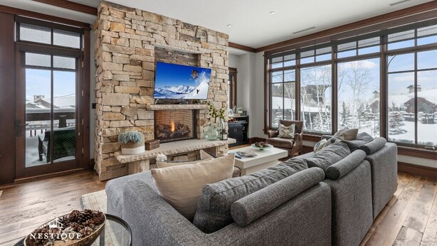 Een moderne woonkamer met een stenen openhaard, een grote flatscreen televisie en een comfortabele hoekbank.