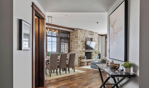 A modern interior with a stone fireplace, dining area, and a large framed artwork.