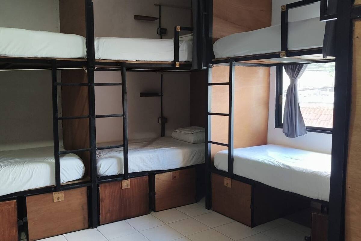 Habitación con literas de madera y ropa de cama blanca.