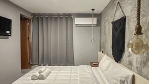 Ein modernes Schlafzimmer mit einem großen Bett, einer Hängelampe und einer Klimaanlage an der Wand.