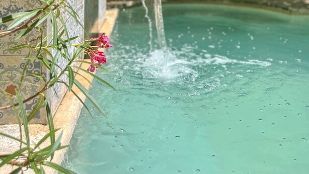 Ein Pool mit Wasserspiel und Fliesenwänden.