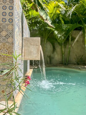 Une piscine agrémentée d’un élément décoratif aquatique et dont les parois sont recouvertes de carreaux.