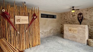 Ein Spa-Raum mit Steinwand, einer Holzbank, einem kleinen Hocker, einem Empfangstisch und einem Deckenventilator.