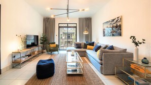 A modern living room with a sofa, coffee table, TV, and decorative items. - Luxury 2bedroom in Dubai Downtown - Burj Views (Dubai)