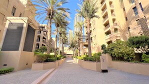 A residential area with high-rise buildings, palm trees, and a paved walkway. - Luxury 2bedroom in Dubai Downtown - Burj Views (Dubai)