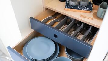 Un cajón de cocina con platos, tazones y utensilios azules.