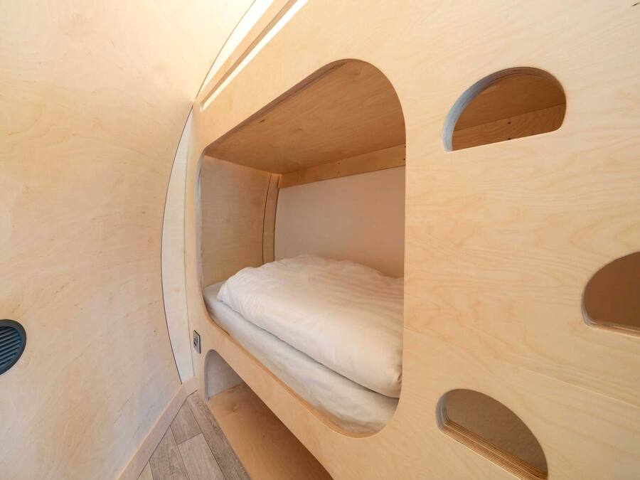 A compact, wooden interior with a bunk bed and a small window.
