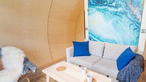 A cozy room with a sofa, a small table, and a furry chair. - Kinelarty Luxury Glamping Pods (Downpatrick)
