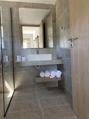 A modern bathroom with a large mirror, a sink, and a towel rack.