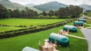 A green landscape with a road, a green building with a dome structure, and a grassy field. - FURTHER.SPACE at Leitrim Lodge (Newry)