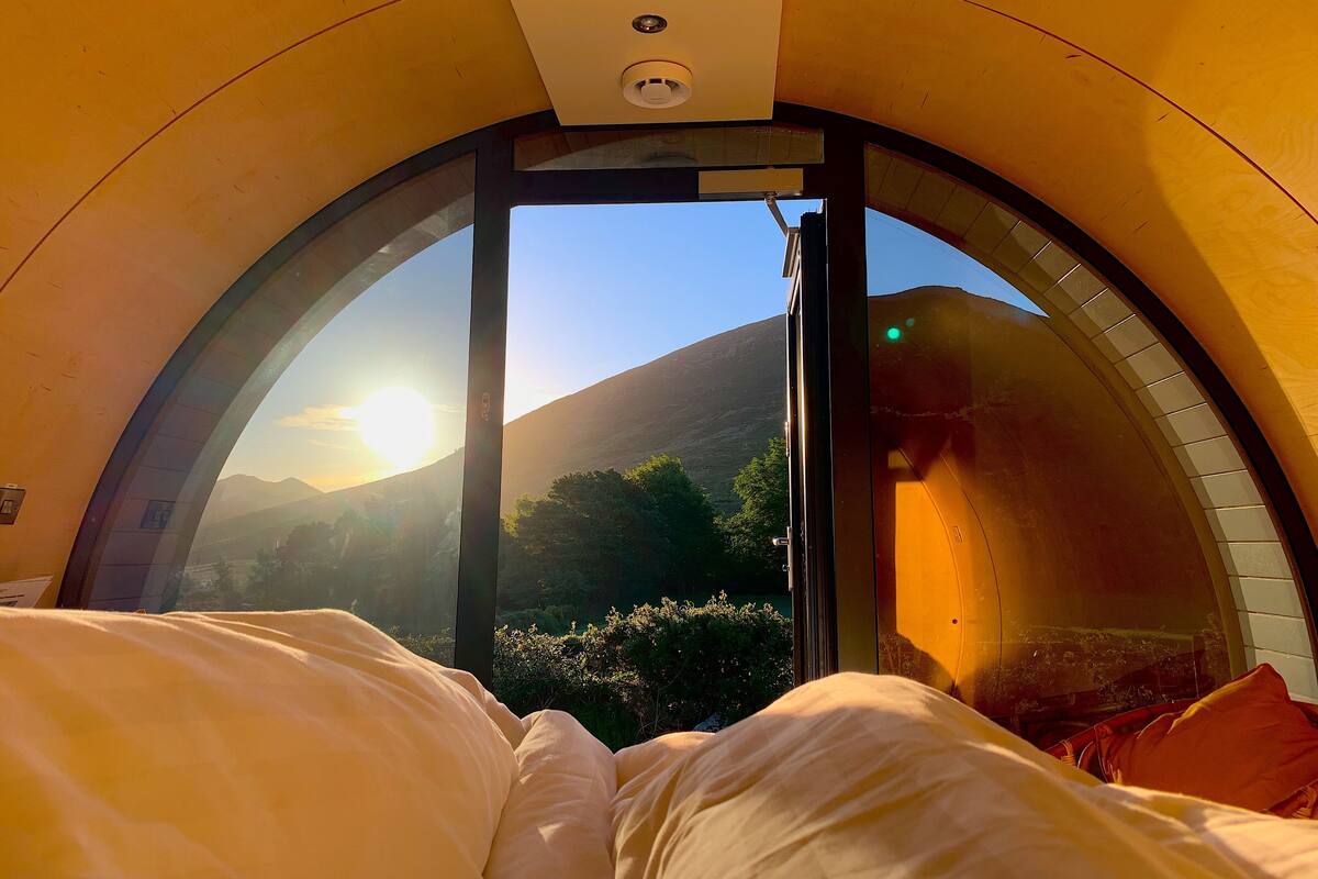 Een kamer met een bed, een raam en uitzicht op een berg.