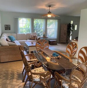 Cozy living area with a dining table for four, wicker chairs, and a sofa.