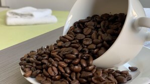 A white cup filled with coffee beans spilling onto a table. - Rhöner Ferienwohnung (Dermbach)