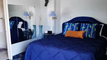 Un dormitorio con una cama grande, dos lámparas de noche, una mesita de noche, un espejo y un adorno en la pared.