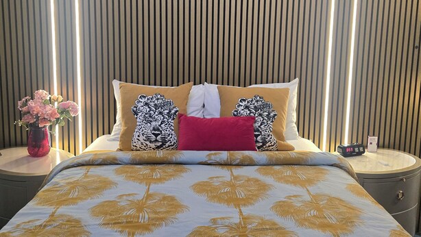 A hotel room with a bed, a nightstand, a vase of flowers, and a clock. - Harry's Man Cave: The New Star Motel Experience (Moreno Valley)
