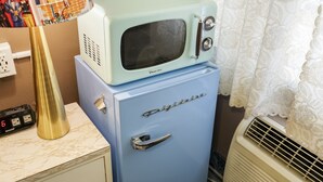 A vintage blue refrigerator with a microwave on top, a gold lamp, and a Sharp digital clock. - Harry's Man Cave: The New Star Motel Experience (Moreno Valley)
