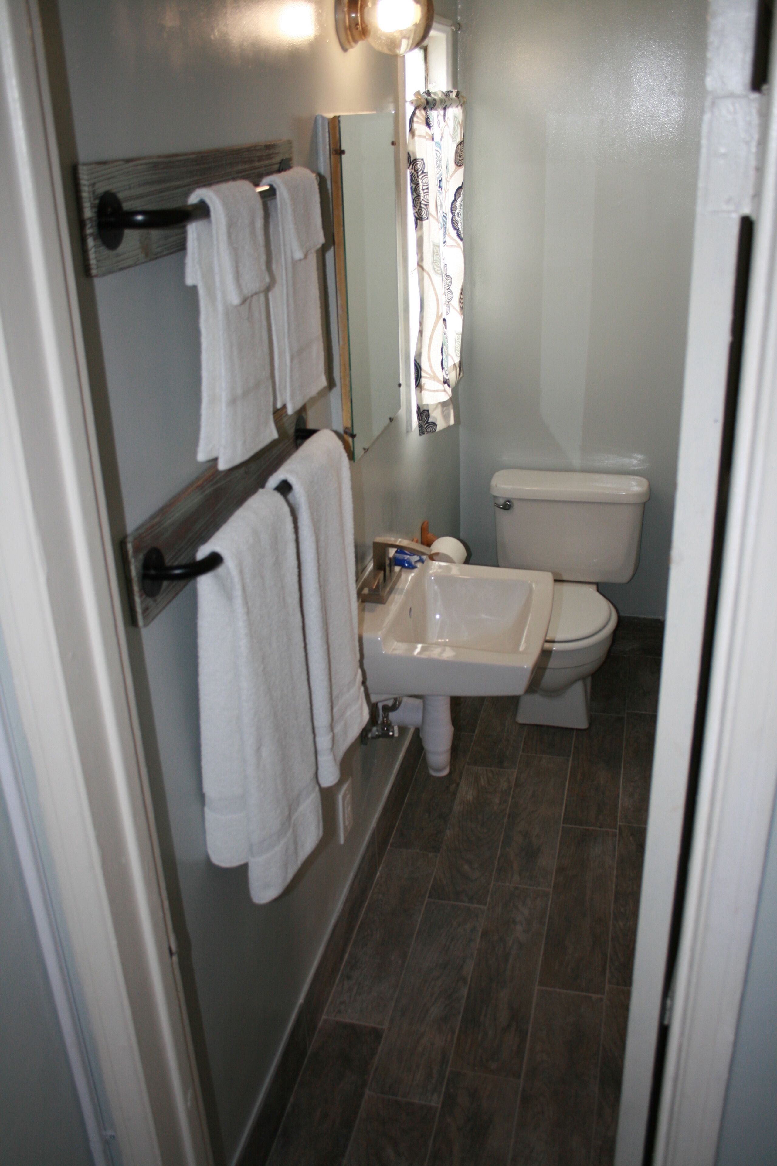 Un baño con inodoro, lavamanos y perchero para toallas.