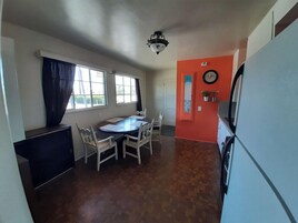 Una cocina compacta con una mesa y sillas, un refrigerador y un reloj en la pared.