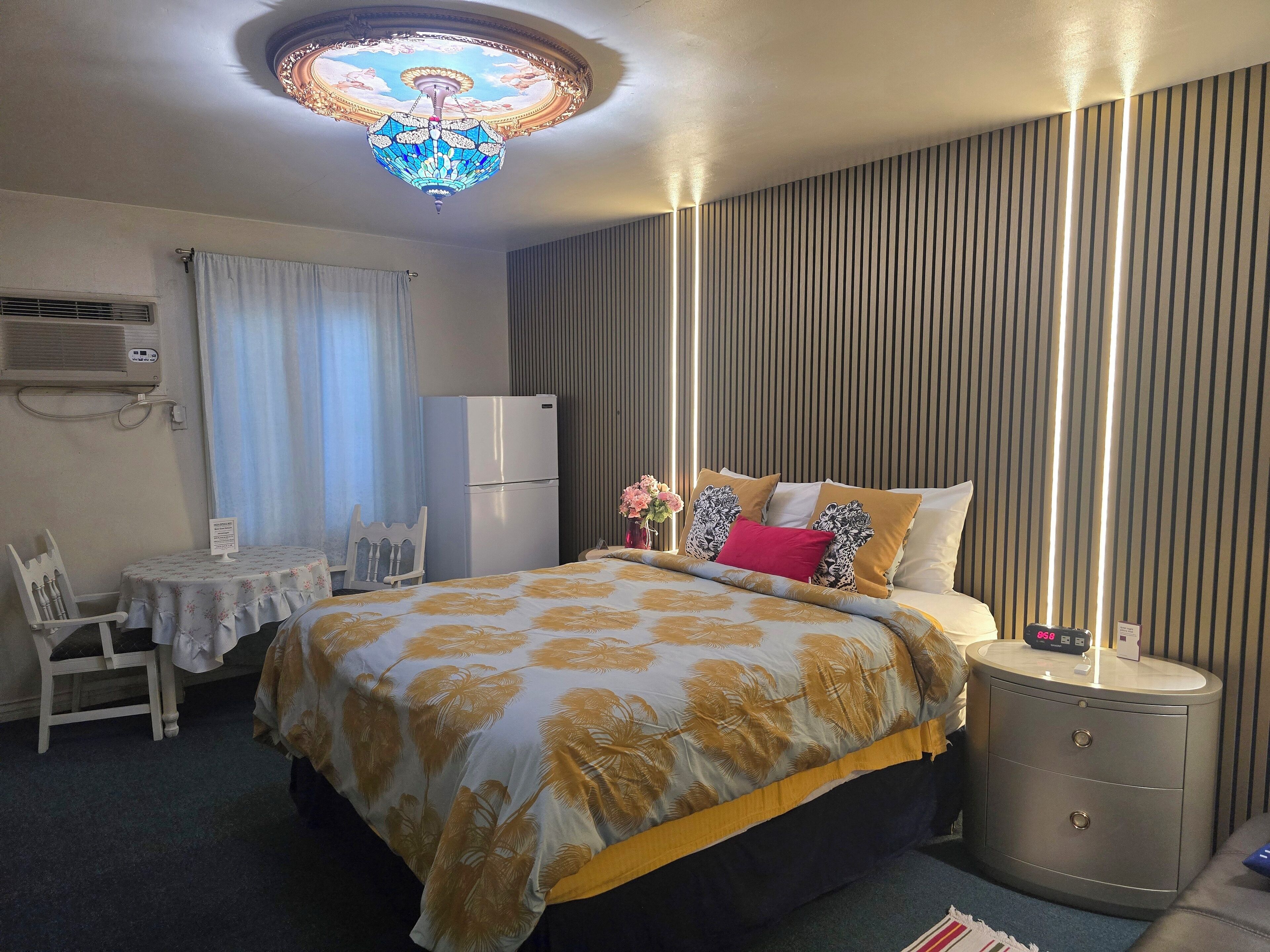 A hotel room with a bed, bedside table, and a ceiling light fixture.
