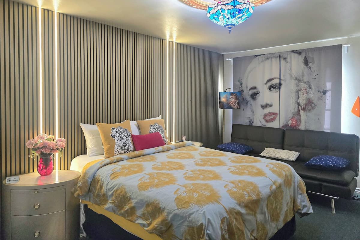 A modern bedroom with a large bed, a decorative ceiling light, and a wall mural.