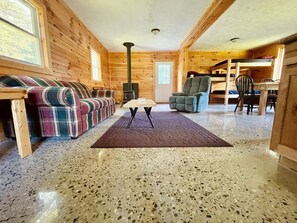Un intérieur de chalet chaleureux avec un canapé à carreaux, un fauteuil, une table et une cheminée.