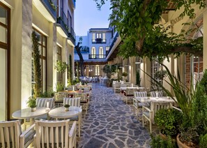 Un patio con mobiliario exterior, suelo de piedra y plantas en macetas.