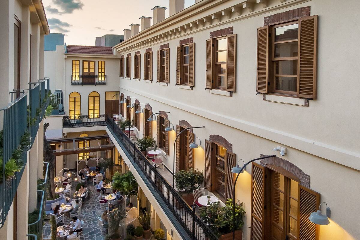 A courtyard with outdoor seating, a staircase, and a building facade with shutters.