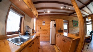 A compact kitchen with wooden cabinets, a sink, a refrigerator, and a window providing natural light. - Ecolodge And Wines with native nature, where Chilean wine was born. (Guarilihue)