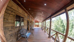 A wooden cabin with a covered porch, wooden walls, and large windows. - Ecolodge And Wines with native nature, where Chilean wine was born. (Guarilihue)