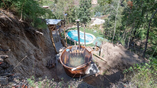 A hot tub in a natural setting with a pool and wooden deck. - Ecolodge And Wines with native nature, where Chilean wine was born. (Guarilihue)