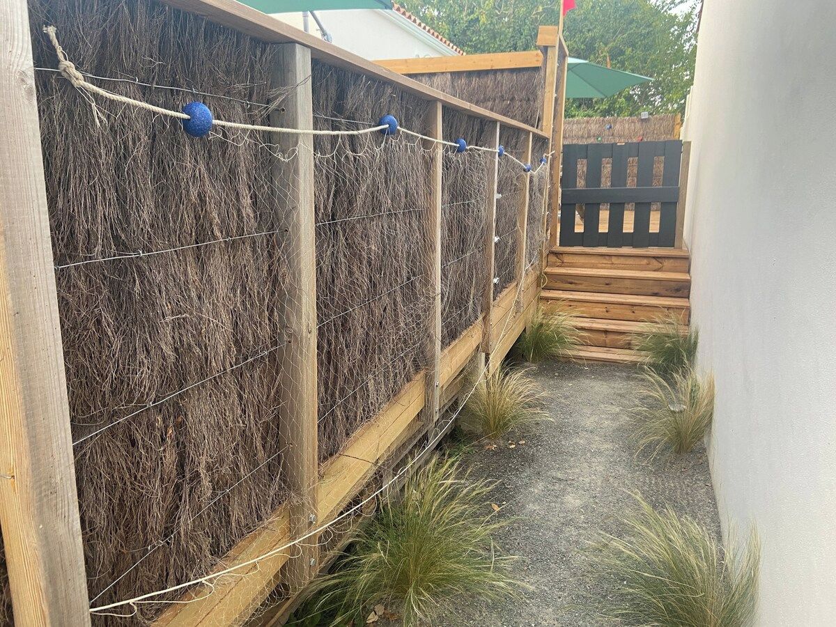 Une structure en bois avec un mur en treillis métallique, une corde ornée de boules bleues et une terrasse en bois.