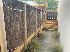 A wooden structure with a wire mesh wall, a rope with blue balls, and a wooden deck.