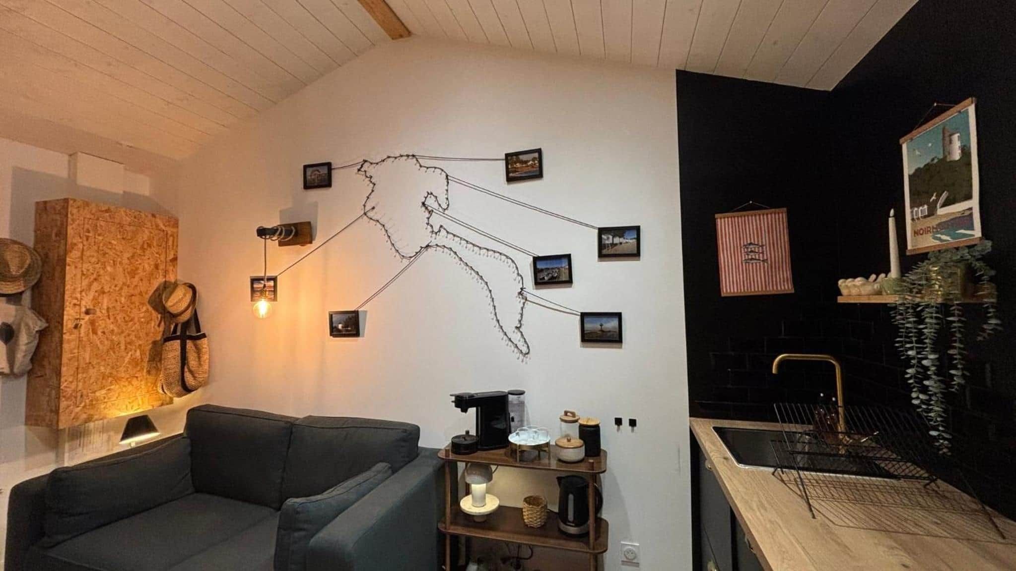 Ett modernt vardagsrum med en grå soffa, ett soffbord i trä och en konstinstallation på väggen.